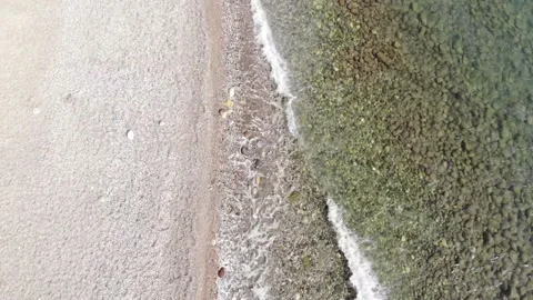 Top view of pebbles under clear water and calm waves of the sea rolling on the 库存影片 167636383