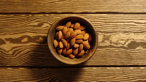 TOP VIEW: Peeled almonds appear in wooden cup and full this cup - Stop motion Stock Footage 96799863