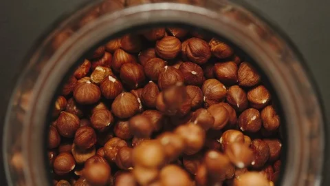 TOP VIEW: Peeled nuts falling into a glass jar - Slow Motion Stock Footage 103363205