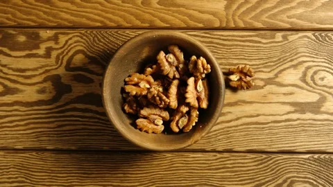 TOP VIEW: Peeled walnuts fall into wooden cup - Slow motion Stock Footage 96193060