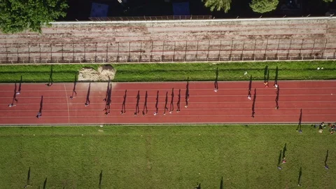 Top View of People Running on Running Track Creating Long Shadow Stock Footage 113427042