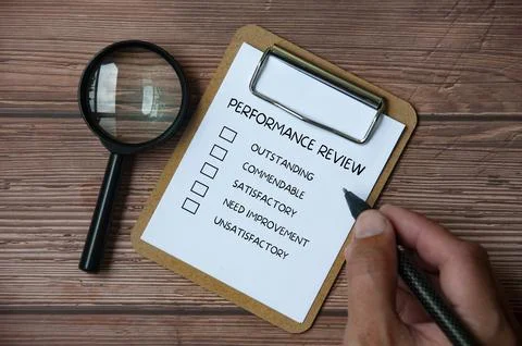 Top view of performance review checklist on clip board with hand holding a .. Stock-Fotos
