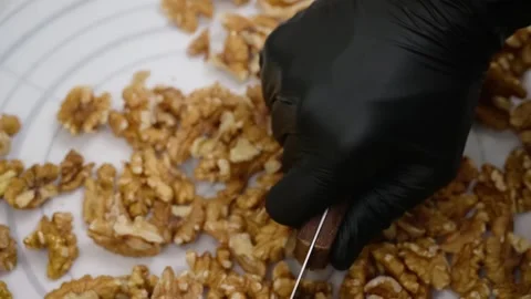 Top view of a person with black gloves chopping fresh walnut kernels for a desse Stock Footage 337751532