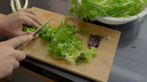 Top view of person hands chopping fresh green lettuce on wooden cutting board Stock Footage 338143221