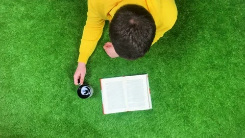 Top view of person reading a book and drinking tea on green grass, flipping page 스톡 동영상 188958542