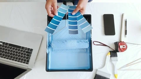 Top view of a person selecting blue paint swatches above a roller tray. Stock Footage 309509097