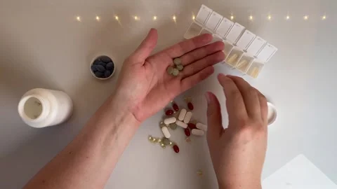 Top view of person sorting pills and vitamins into a weekly pill organizer .. Video stock 318672533