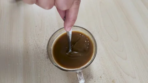 Top View of Person Stirring Instant Coffee in Glass Mug with Spoon Stock Footage 346587414