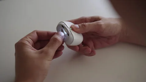 Top view of person using electric nail clipper with built-in light, providing Stock Footage 318471097