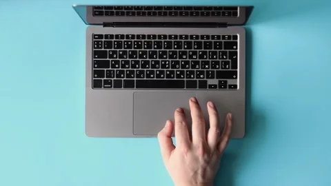Top view of a person using a laptop on a light blue background. Stock Footage 325036274