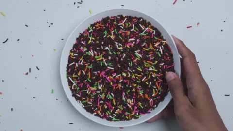Top view of picking up and putting down a plate of chocolate sprinkles Stock Footage 280453068