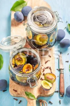 Top view of pickled plums in jar on blue table Stock Photos