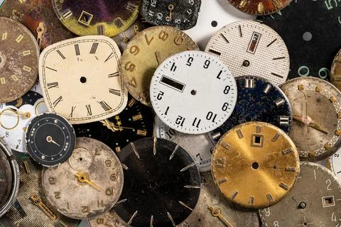 Top view on pile of old worn clock dials. Aged scratched round watch faces with Stock Photos