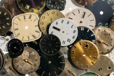 Top view on pile of old worn clock dials. Aged scratched round watch faces with Stock Photos