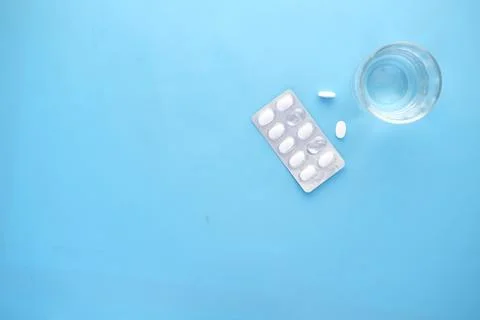 Top view of pill of blister pack and glass on water on blue Stock Photos