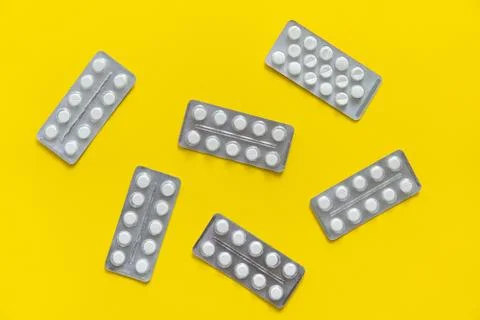 Top view on the pills in the package. White pills on yellow background. Medicine Stock Photos