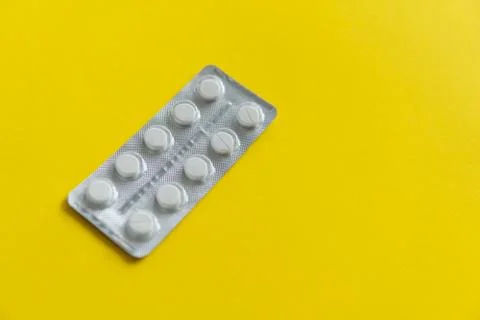 Top view on the pills in the package. White pills on yellow background. Medicine Stock Photos
