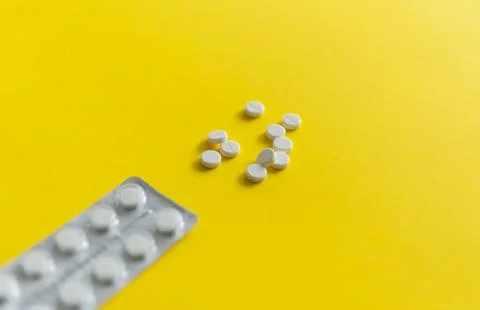 Top view on the pills in the package. White pills on yellow background. Medicine Stock Photos