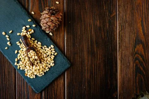 Top view of pine nuts on slate with wooden scoop. Stock Photos