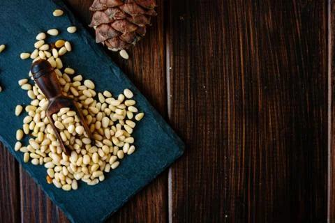 Top view of pine nuts on slate with wooden scoop. Stock Photos