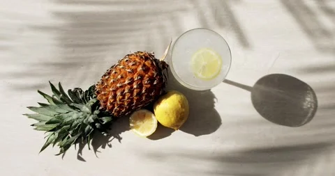 Top view of pineapple, lemon, palm tree shadows and a glass of soda Stock Footage 153037976