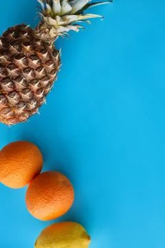 Top view of pineapple, oranges and lemon isolated on blue background Stock Photos