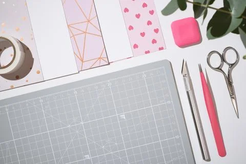 Top view of pink craft tools and paper on grey cutting mat. Copyspace. Stock Photos
