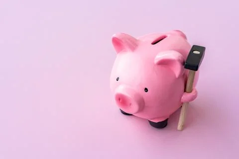 Top view of pink piggy bank with hammer on pink background. Stock Photos