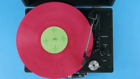 Top view of pink vinyl on Record player with blue background and green label Stock Footage 218629588