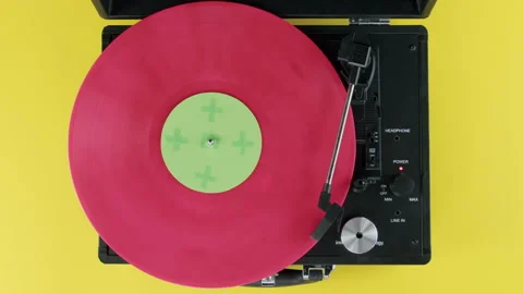 Top view of pink vinyl on Record player yellow background with green label Stock Footage 218629798