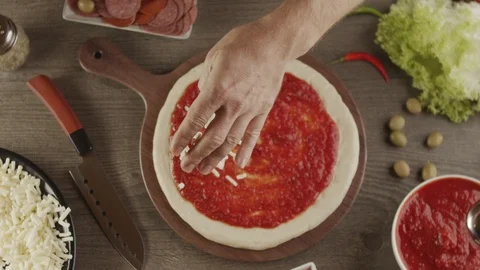Top view of pizza base with tomato sauce add cheese. Slow motion video Stock Footage 123996122