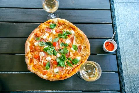 Top view of pizza with fresh basil and cheese, two glasses of white wine on the Stock Photos