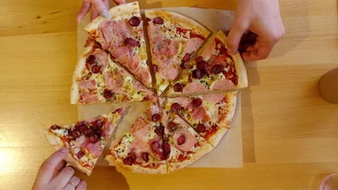 Top view of the pizza on the table. Hands disassemble slices of pizza. Video stock 220345189