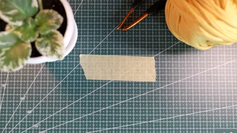 Top view of placing blank tape sticker near knitting yarn and flowerpot Stock Footage 338183874