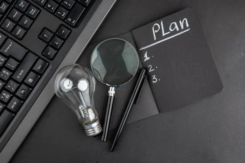 Top view plan written on black notepad lupa keyboard light bulb pen on blac.. 写真素材