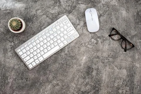 Top view plaster background with keyboard, glasses, mouse and a cactus. - Cop Stock Photos
