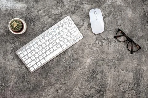 Top view plaster background with keyboard, glasses, mouse and a cactus. - C.. Stock Photos