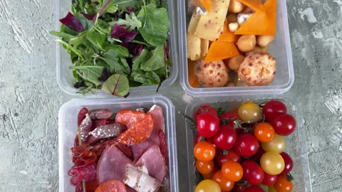 Top view of plastic containers with vegetables, cheese and sausages, food storag Stock Footage 304458934