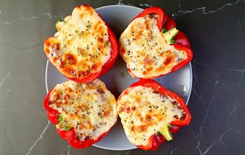 Top View of a Plate of Delectable Stuffed Bell Peppers Isolated on Black Table 스톡 사진
