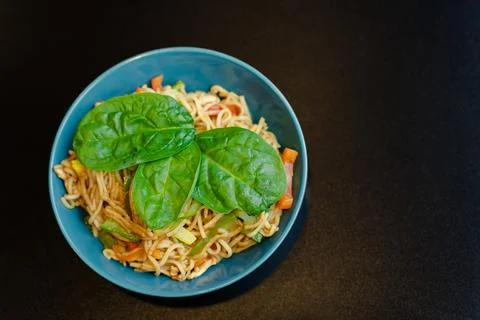 Top view of a plate of spaghetti with vegetables and basil leaves Stock Photos