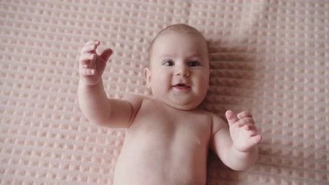 Top view of playful smiling newborn infant lying on his back on the bed Stock Footage 150117943