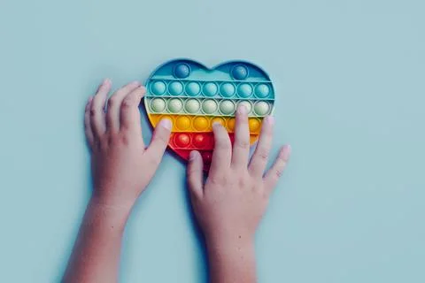 Top view pop it fidget anti stress toy in child hands Stock Photos