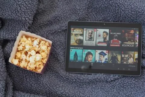 Top view of popcorn box and tablet with netflix on warm blanket Stock Photos