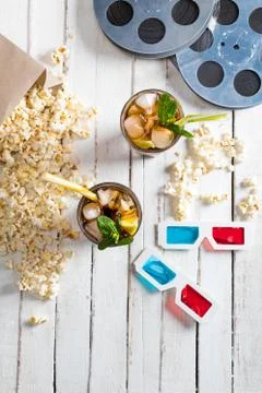 Top view of popcorn with iced tea, film reels and 3D glasses on table, Movi.. Stock Photos