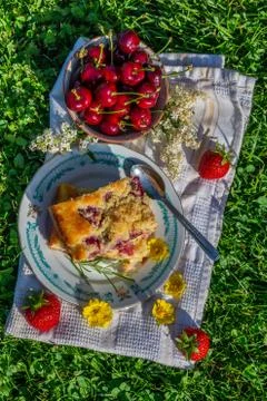 Top view on portion of cherry cake with ripe strawberries around and yellow b Stock Photos