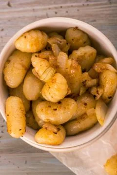 Top view on portion of fried gnocchi with onion in light bowl Stock Photos