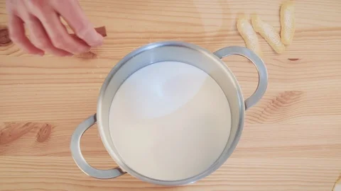 Top view of a pot with milk where a human hand is pouring ingredients Stock Footage 127363470