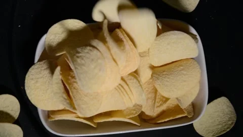 Top view of potato chips being poured onto a plate from a container Video stock 336917396