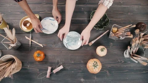 Top view potter making ceramic bowls and plates, woman hands painting color Видео 145030012
