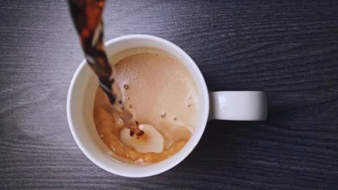 Top view pouring hot coffee into white mug on dark wooden table with foam a.. Stock Footage 339766701